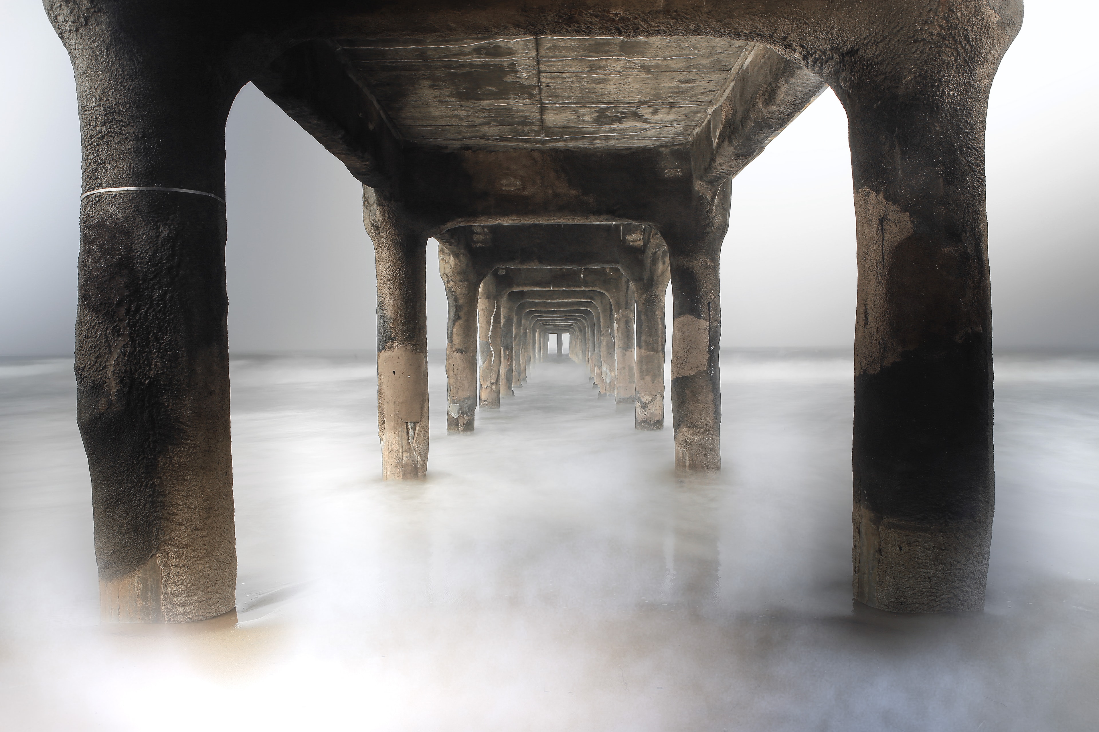 Under the pier looking through concrete pillars with silky misty water