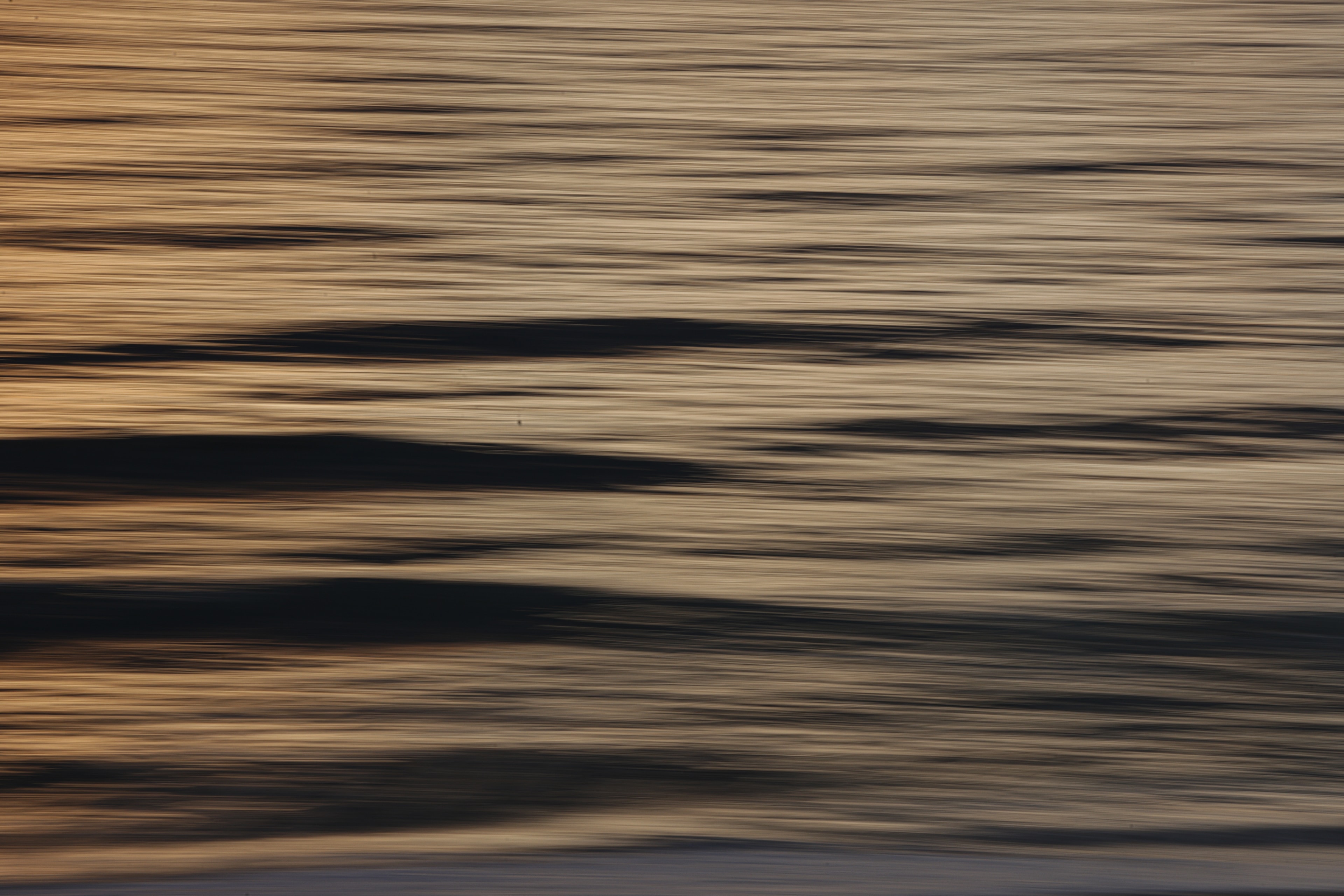 Abstract seascape with warm golden light streaks over dark wave forms