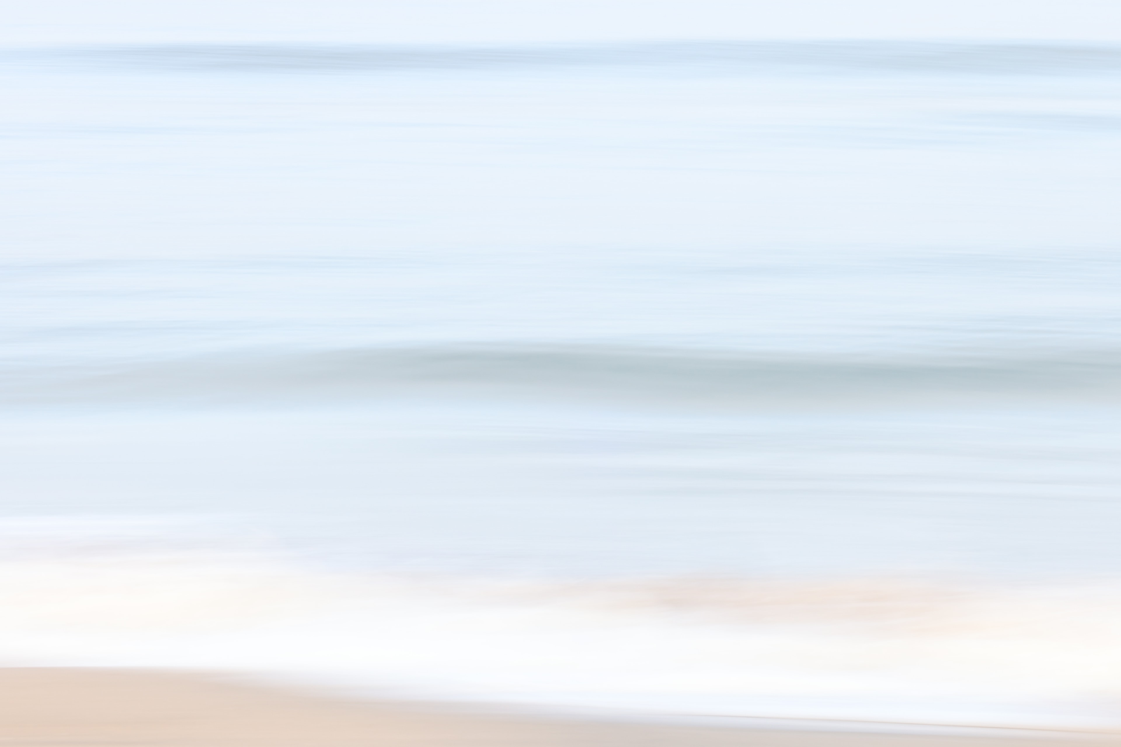 Dreamy seascape with soft blue water and white foam on the shore
