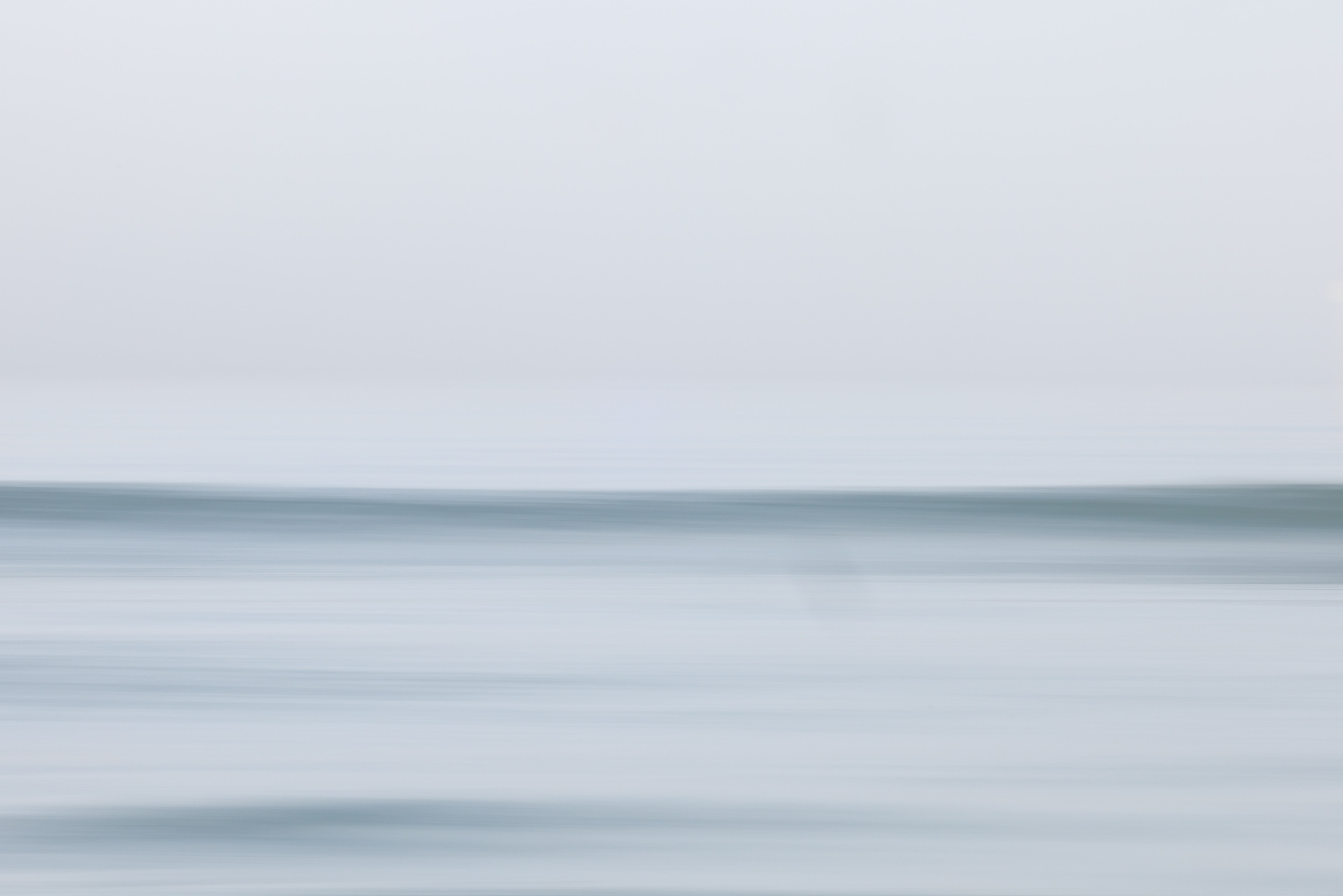 Serene open ocean horizon with smooth silky water and overcast sky
