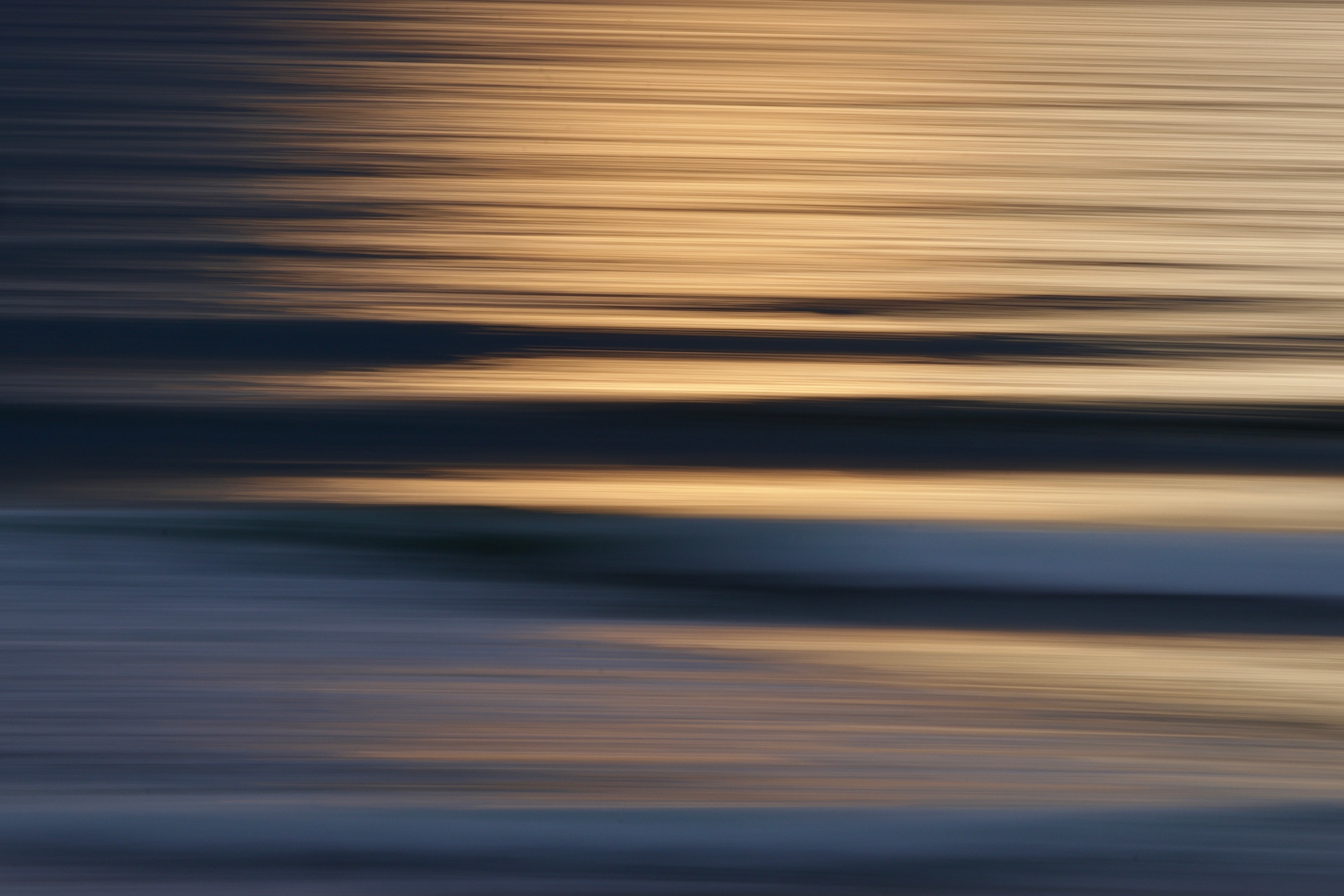 Motion blur seascape with golden and cool blue horizontal bands